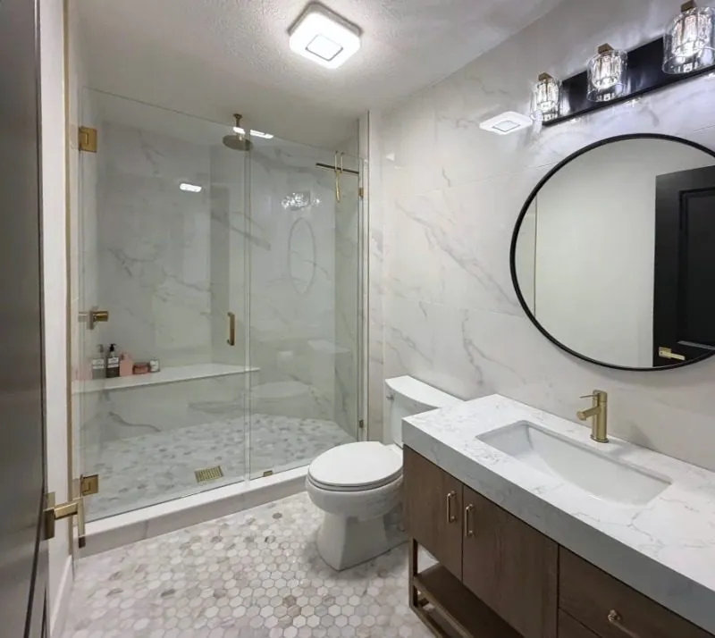 Marble bathroom with glass shower and round mirror