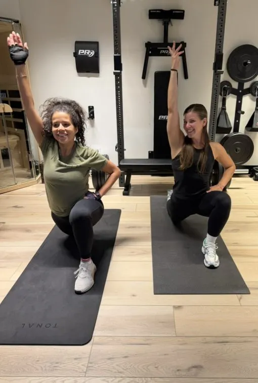 Two women stretching on mats in the home gym