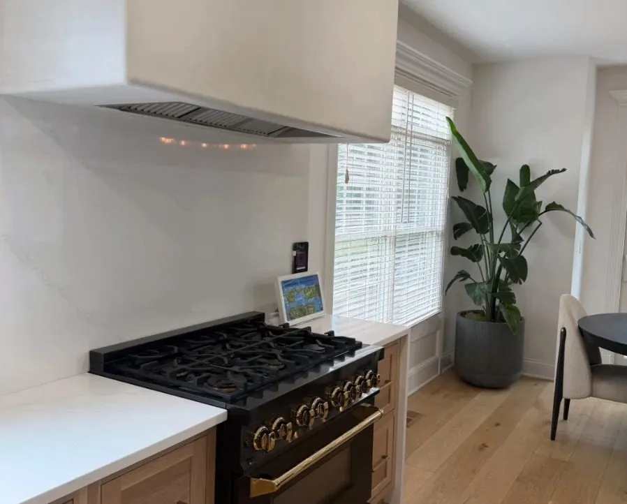 Black range with brass knobs beside a window