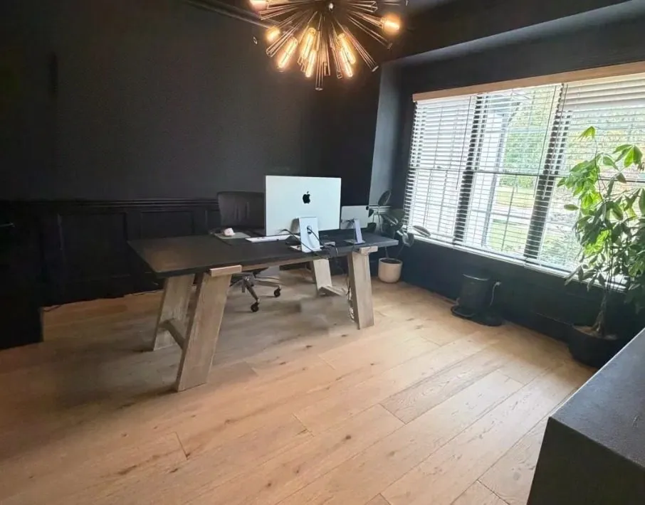 Black-walled office with sputnik chandelier and a wide window