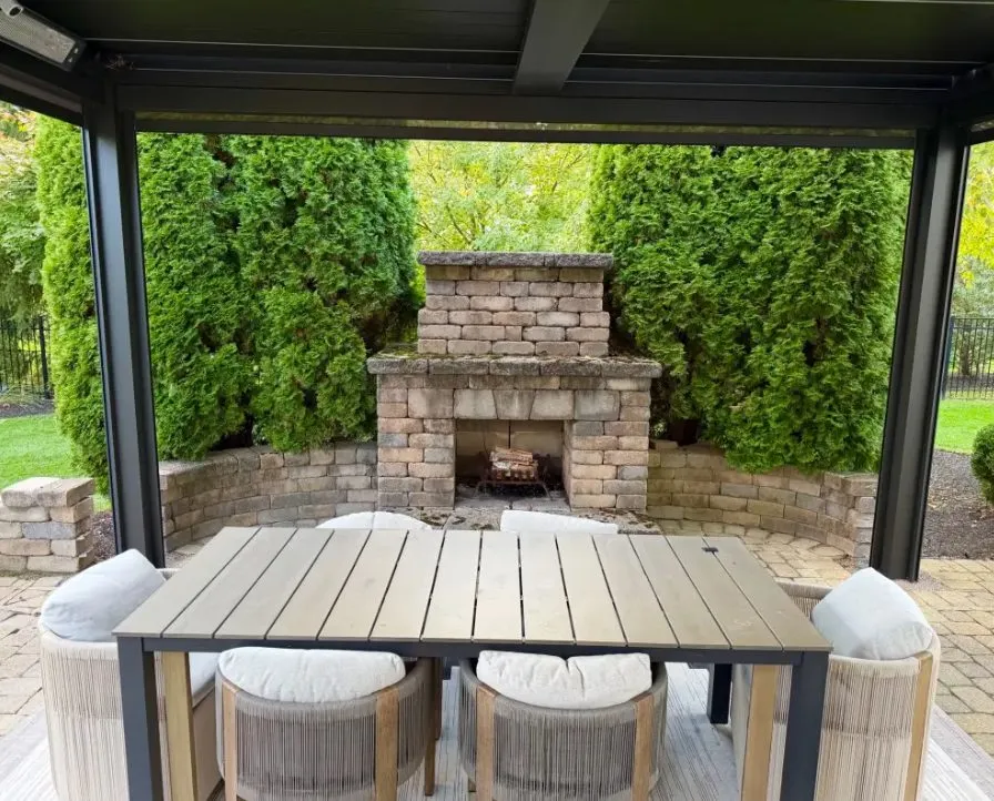 Covered pergola dining table facing a stone fireplace