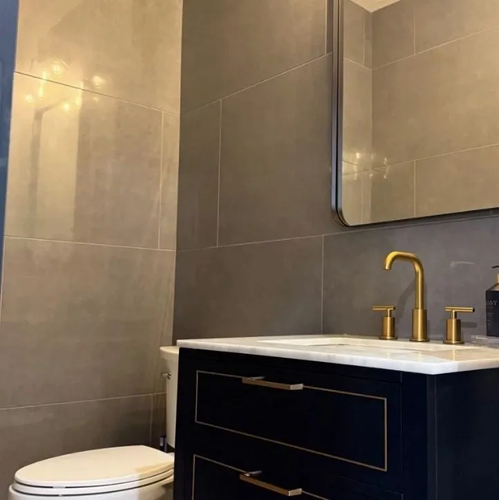 Powder room with navy vanity and brass faucet